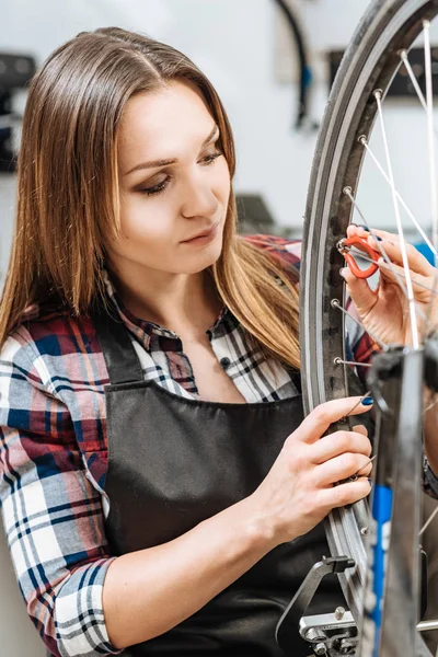 Mujer joven y seria bombeando la rueda de la bicicleta — Foto de Stock