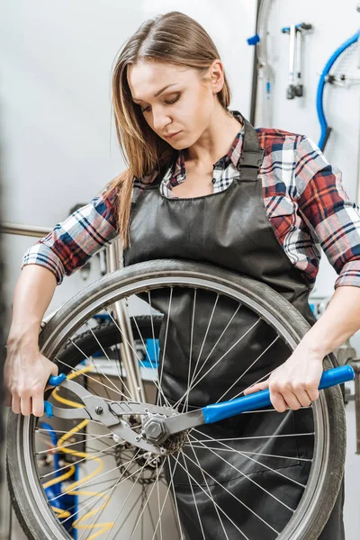 Заботливая ремесленница чинит колесо в мастерской — стоковое фото