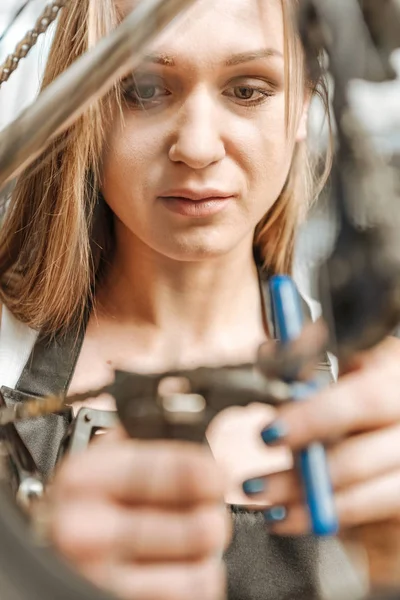 Koncentrerad ganska mekaniker återmontering cykeln i verkstaden — Stockfoto