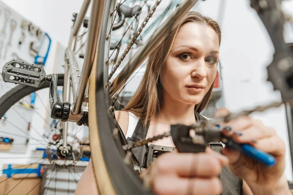 Karismatisk kvinnlig mekaniker återmontering cykeln i garaget — Stockfoto