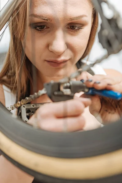 Charming female mechanic repairing the chain of the bicycle — Stock Photo, Image