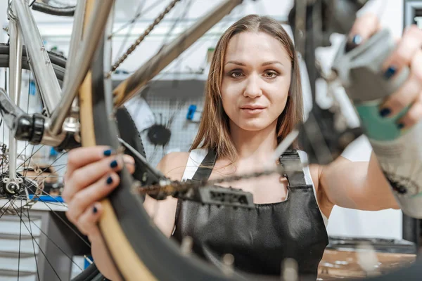 Glada hantverkerska reparera cykeln i verkstaden — Stockfoto