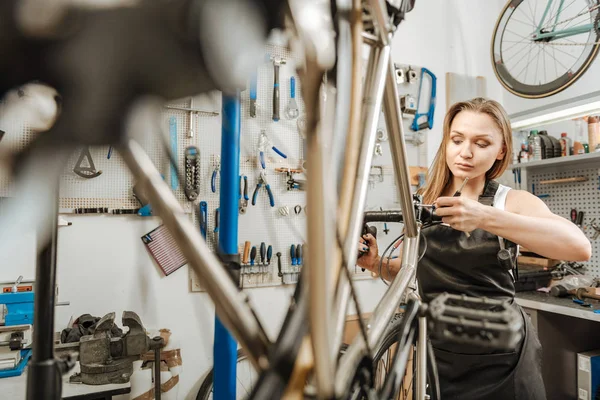 Вежливый механик, ремонтирующий велосипед в ремонтной мастерской — стоковое фото