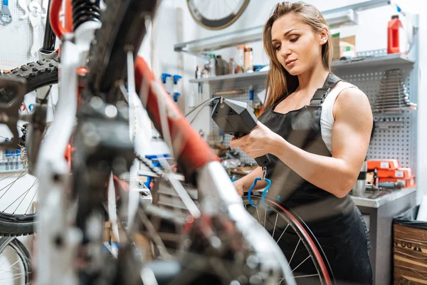 Uppmärksamma charmiga hantverkerska viktning hjulet i garaget — Stockfoto