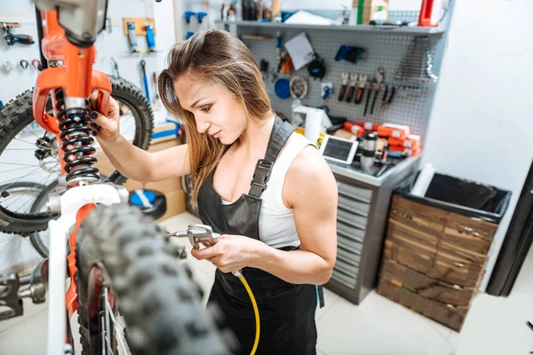 Cheerful female master repairing the mountain bicycle