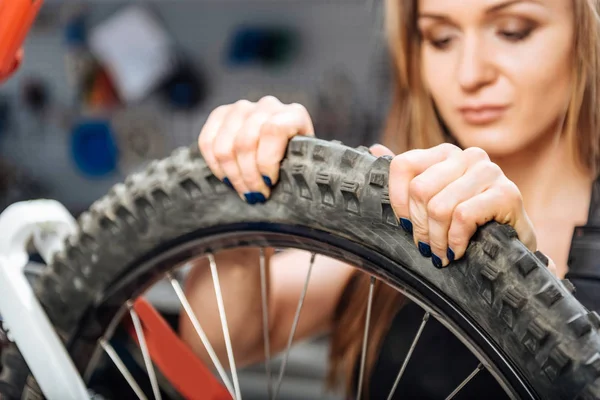 Geconcentreerd vrouwelijke technicus controle op de kwaliteit van de fietswiel — Stockfoto