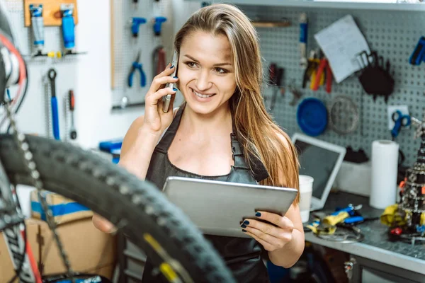 Delighted young mechanic using devices in the repair shop