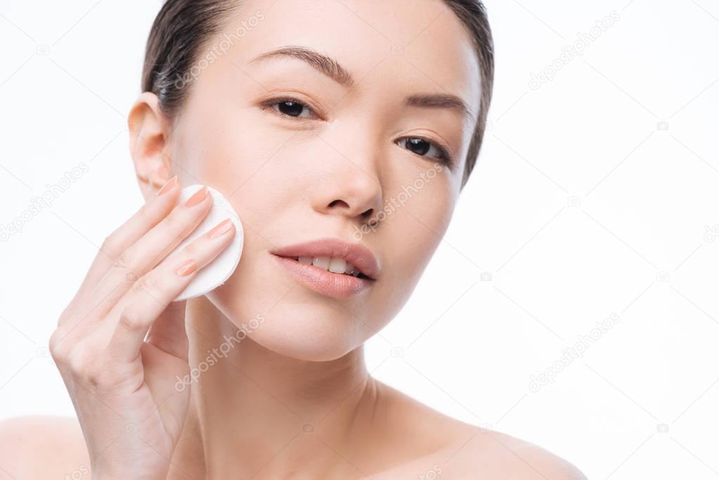 Positive pleasant woman cleaning her skin