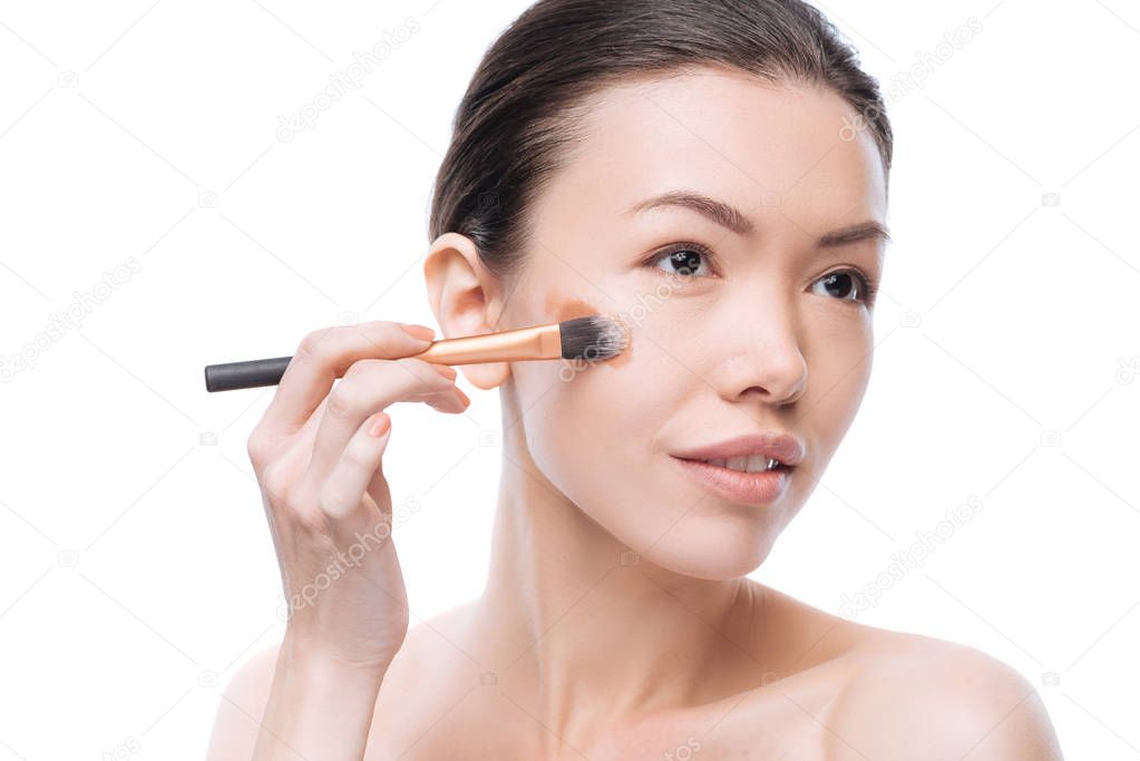 Delighted young woman applying liquid foundation