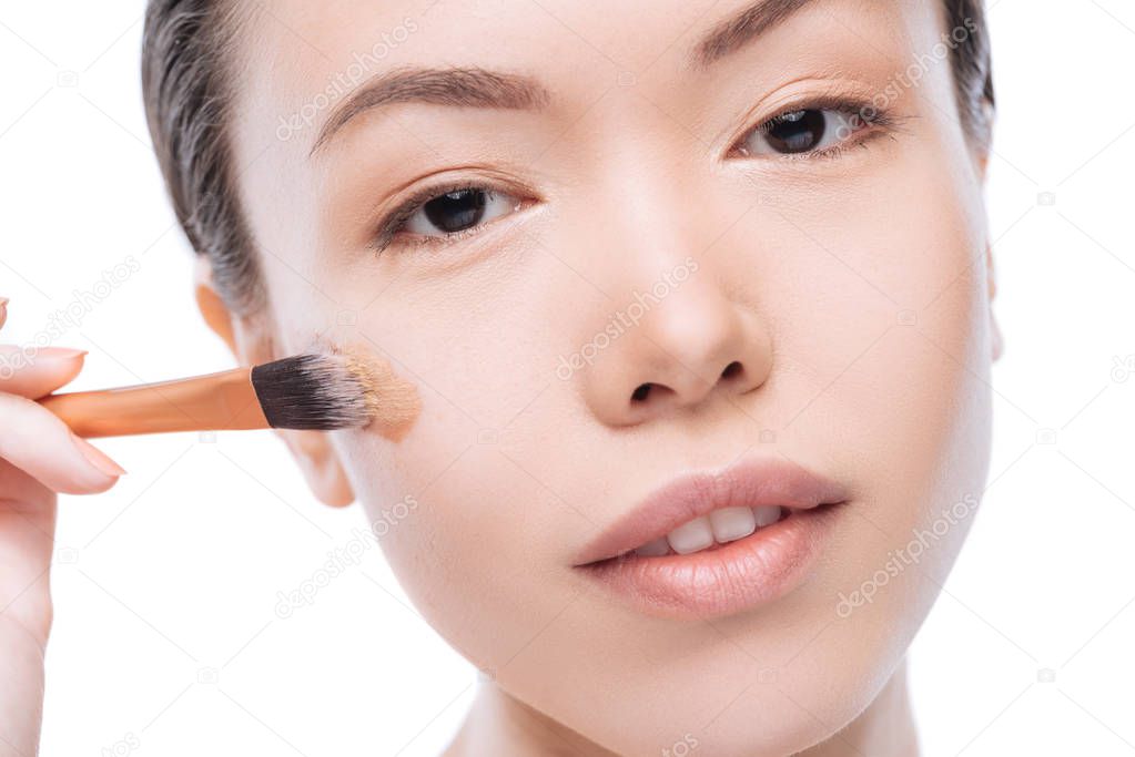 Pretty good looking woman using a cosmetic brush