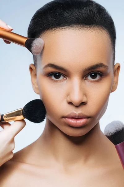 Beautiful cute woman being surrounded by makeup brushes — Stock Photo, Image
