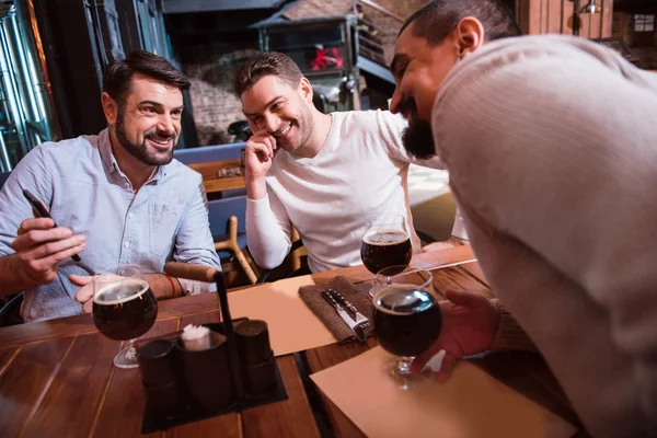 Des hommes positifs joyeux regardant l'écran du smartphone — Photo