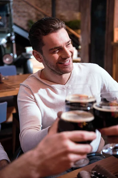 Приятный улыбающийся мужчина пьет со своими друзьями — стоковое фото