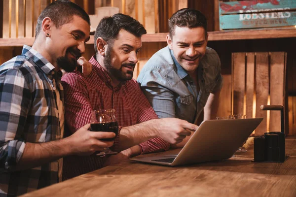 Belgili tanımlık laptop önünde oturan olumlu erkek arkadaşlar — Stok fotoğraf