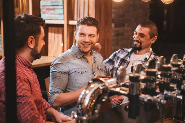 Cheerful positive men sitting at the bar counter