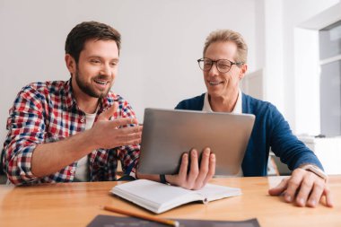 Neşeli pozitif meslektaşları tablet ekrana bakarak