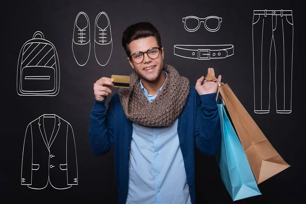 Jovem alegre segurando sacos de compras e mostrando cartão de desconto . — Fotografia de Stock