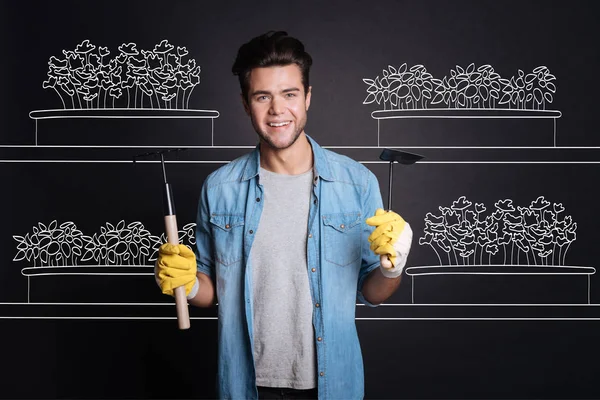 Pleasant attractive man holding gardening tools. — Stock Photo, Image
