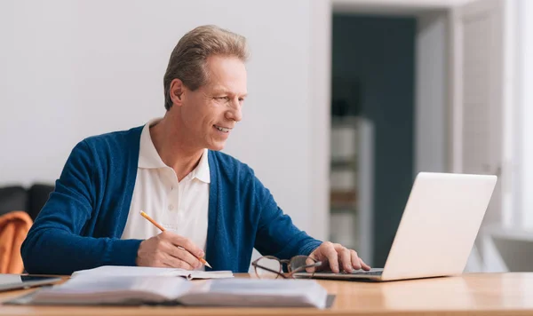 Behaglig grå korthårig man som arbetar på den bärbara datorn — Stockfoto