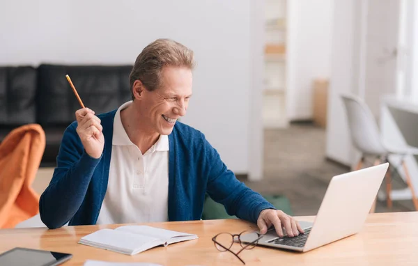 Счастливый веселый мужчина сидит за ноутбуком — стоковое фото