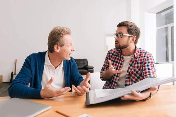 Guapos colegas emocionales sentados juntos en la mesa — Foto de Stock