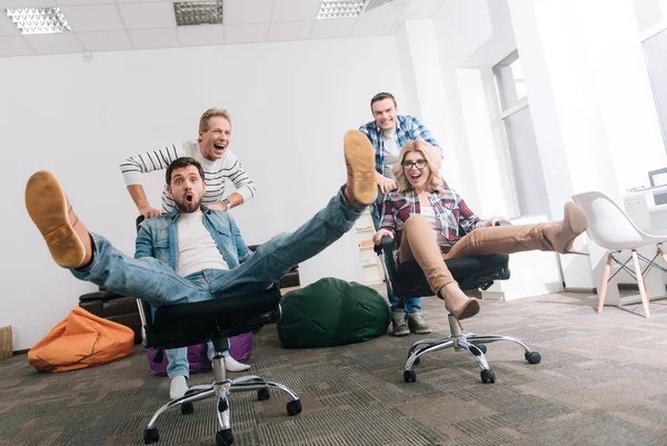 Joyful happy people riding in the office chairs — Stock Photo, Image