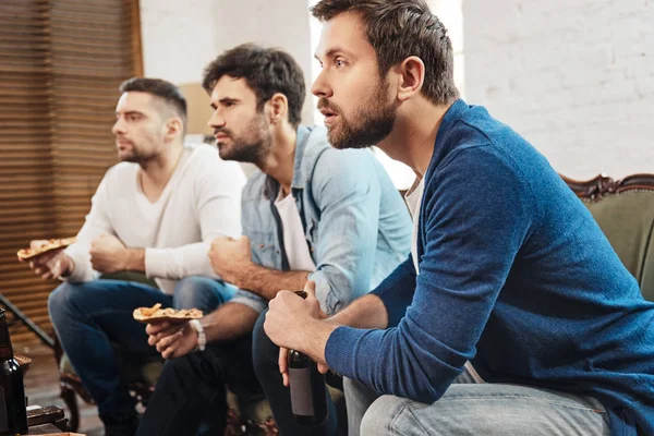 Серьезные сосредоточенные мужчины смотрят футбольный матч — стоковое фото