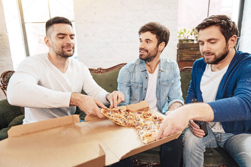 Pleasant male friends sharing a pizza