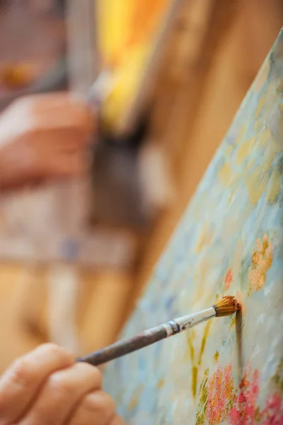 Крупним планом дві руки художника малюють картини пензлями — стокове фото