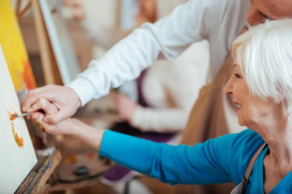 Artist helping his elderly colleague in painting class — Stock Photo, Image