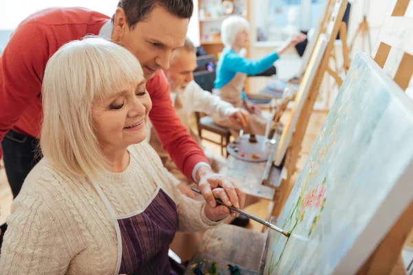 Hombre contento ayudando a anciana en estudio de pintura —  Fotos de Stock