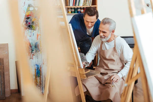 Artista bonito ajudando o homem idoso na pintura — Fotografia de Stock