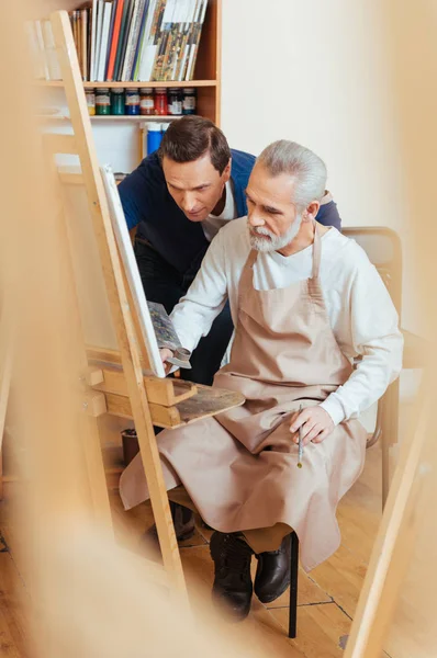 Artista talentoso ajudando o homem idoso na pintura — Fotografia de Stock