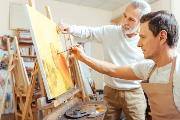 Inspired artist painting with his young colleague. — Stock Photo, Image
