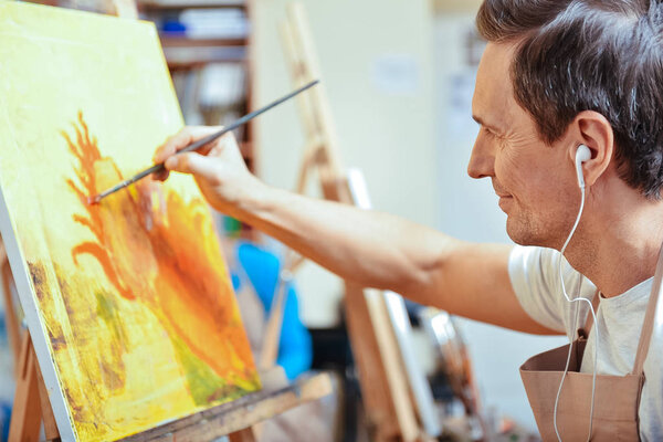 Concentrated artist painting a picture in cozy studio