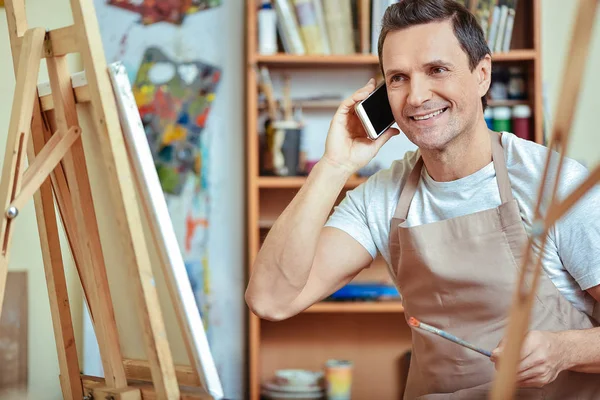 Gelukkig kunstenaar praten over cellphone in schilderij studio — Stockfoto