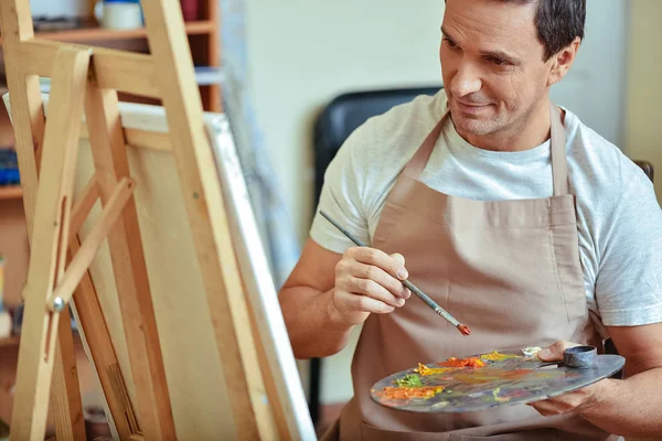Concentrated artist holding a brush and palette — Stock Photo, Image