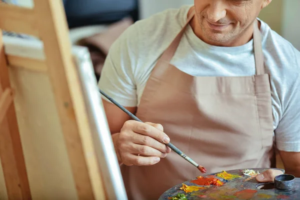 Närbild av koncentrerad konstnär håller en pensel och palett — Stockfoto