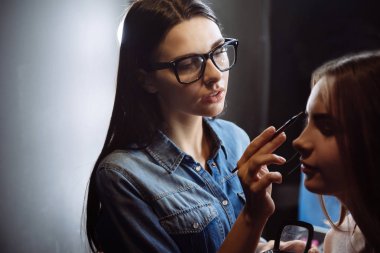 Güzel iyi görünümlü visagiste bir kaş fırçası kullanarak