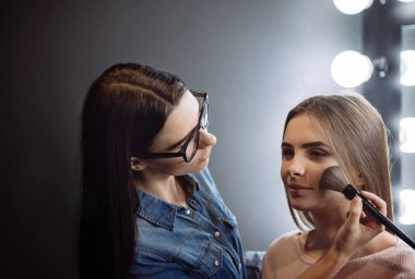 Bir toz fırça kullanarak sevimli çekici makyaj sanatçısı