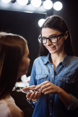 Bir allık paleti tutan iyi görünümlü çekici makyaj sanatçısı