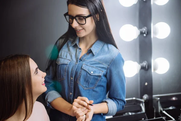 Roztomilá brunetka vizážistiku, při pohledu na její klient — Stock fotografie