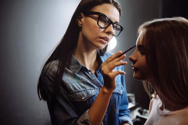 Agradable visagiste bien parecido aplicando maquillaje de cejas — Foto de Stock