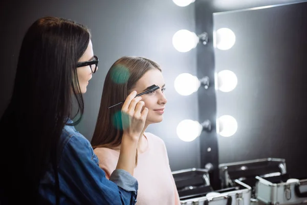 Pretty attractive makeup artist combing the eyebrows — Stock Photo, Image