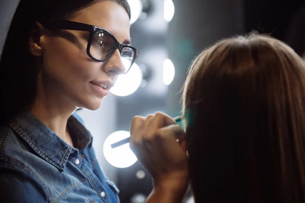 Agradable artista de maquillaje agradable usando un lápiz cosmético —  Fotos de Stock