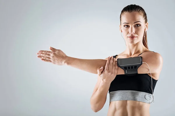 Athletic woman doing stretching on a grey background — Stock Photo, Image