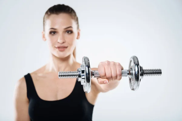 Chica motivada haciendo ejercicio con mancuernas sobre un fondo gris —  Fotos de Stock