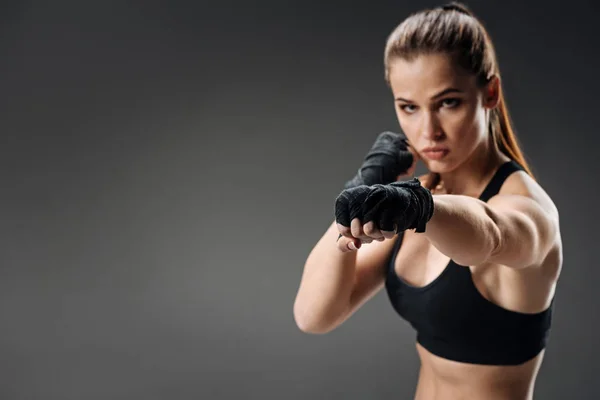Mächtige Frau boxt vor grauem Hintergrund — Stockfoto