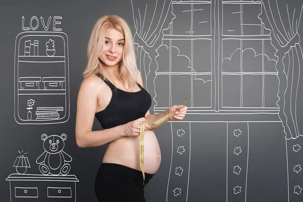 令人愉快的怀孕妇女，拿着卷尺 — 图库照片