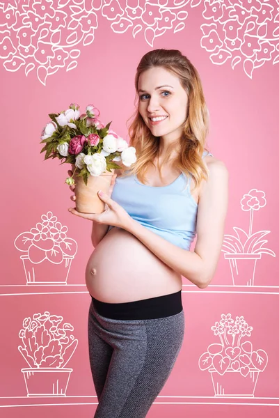 Çiçek açan çiçekler tutan olumlu hamile kadın — Stok fotoğraf